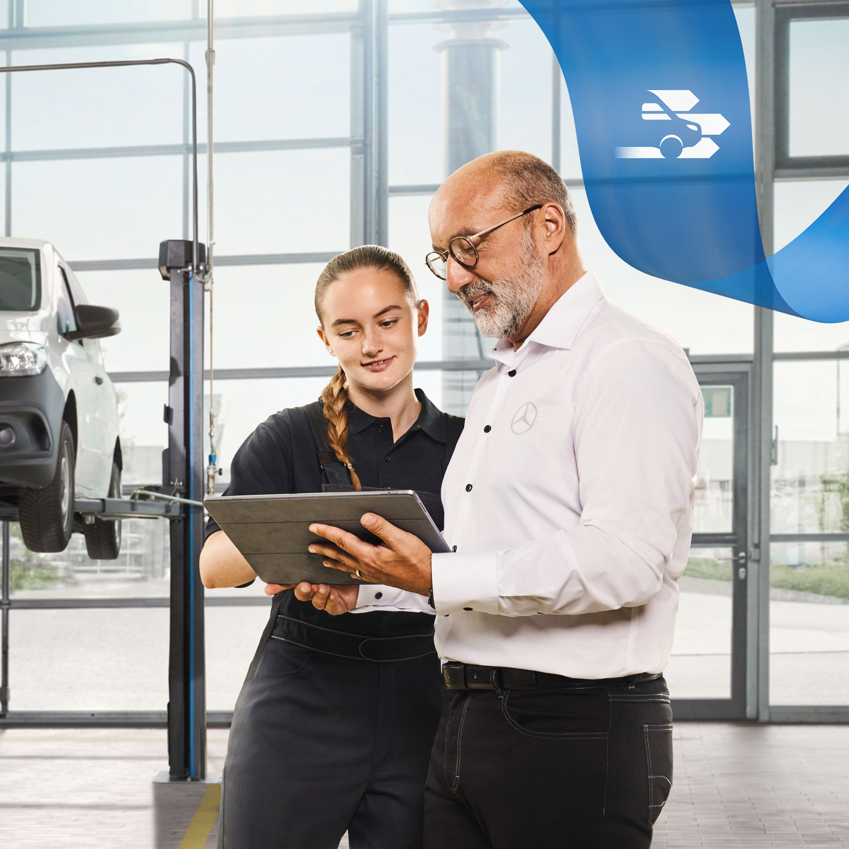 Mercedes-Benz | Maintenance Deux employés discutent de l'entretien d'un véhicule industriel à côté d'un utilitaire léger Mercedes-Benz sur cric dans l'atelier.