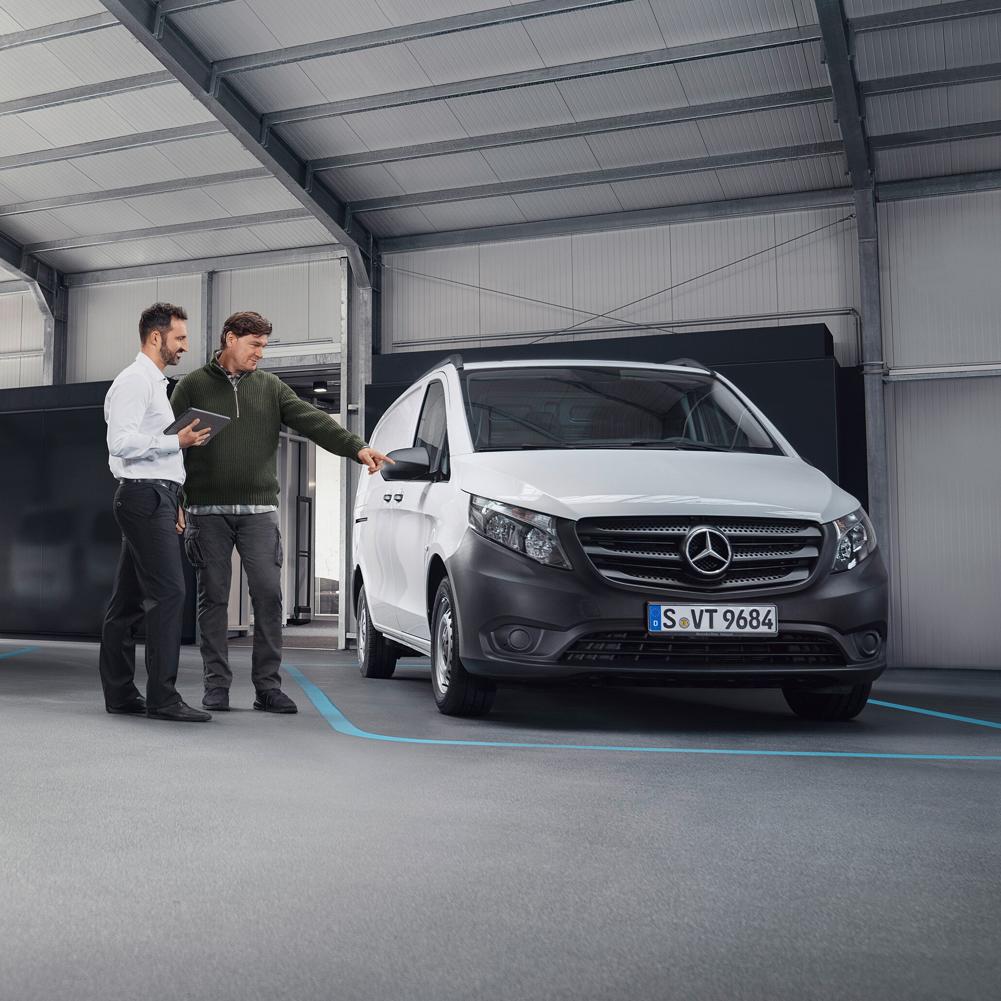 Mercedes-Benz Kundenbetreuer mit Kunde im Betrieb eines Service-Partners vor einem Transporter.