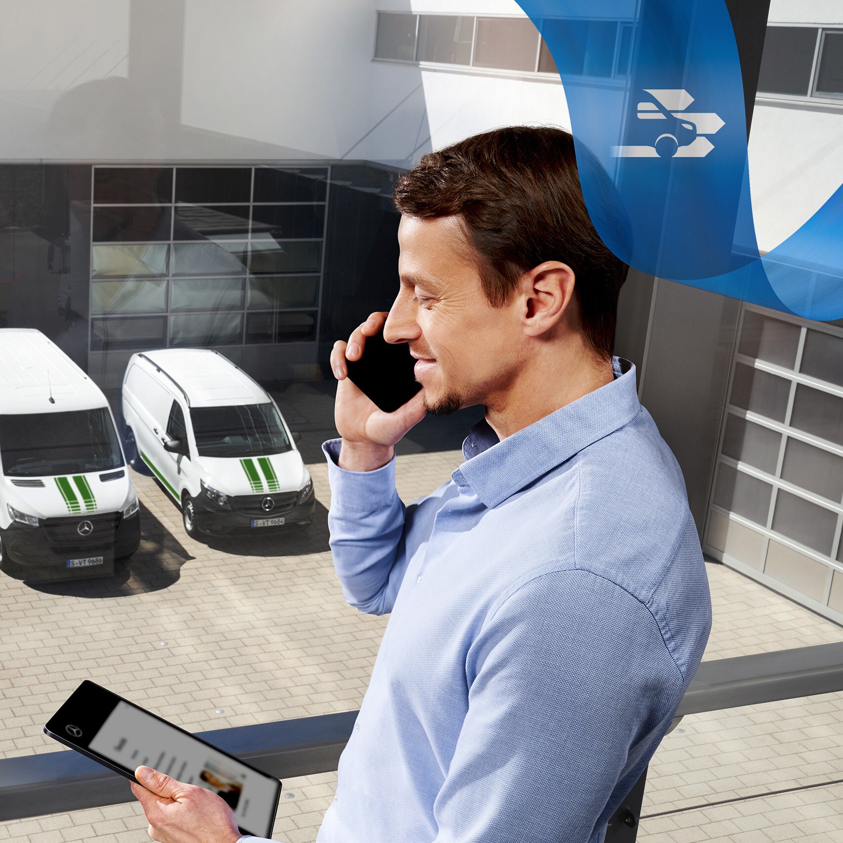 Un homme parlant au téléphone, tout en regardant une tablette, avec une série d'utilitaires légers Mercedes-Benz en arrière-plan.