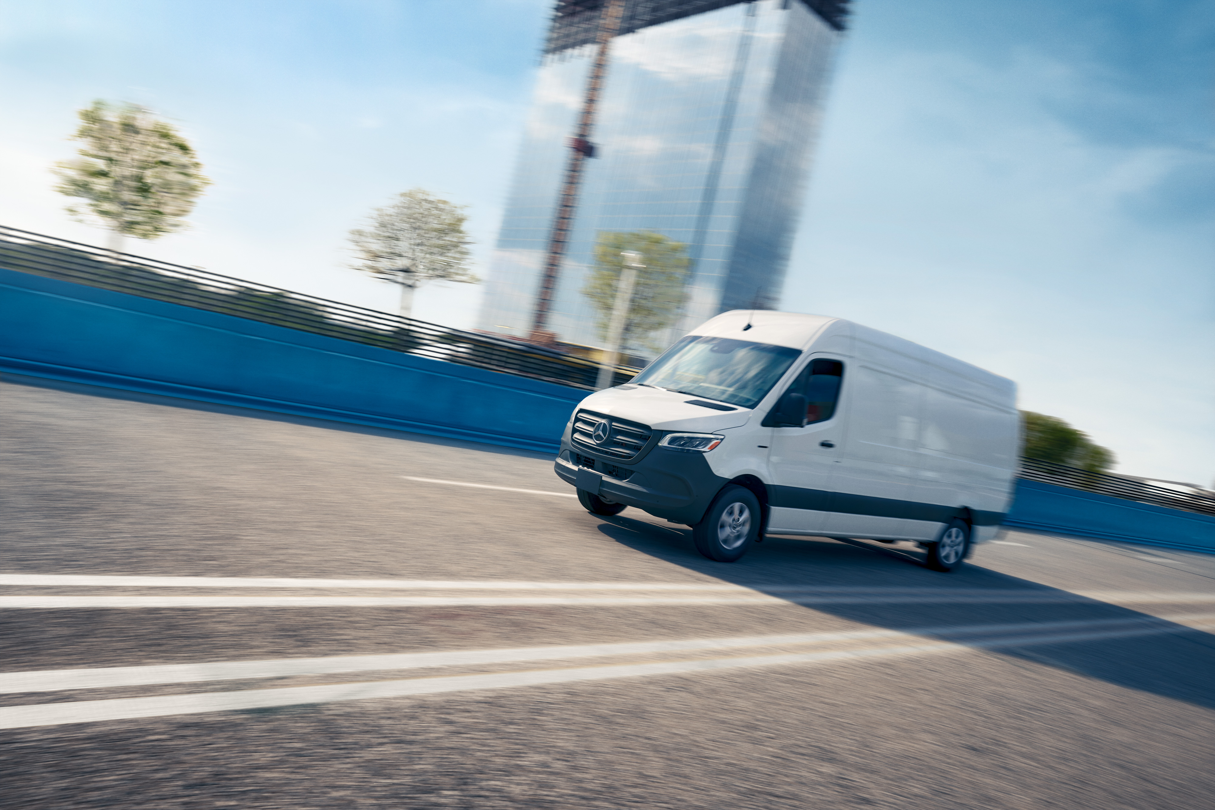 Mercedes-Benz | Fahrzeugtechnologie | Onboard Service App Ein weißes Nutzfahrzeug fährt auf einer Straße – Werbung für die Mercedes-Benz Service App mit Online-Terminbuchung.