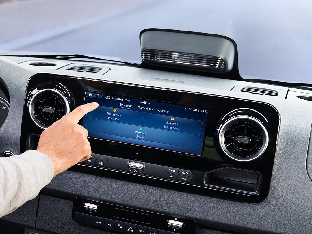 Fahrer nutzt die Service App auf dem Fahrzeugdisplay, um Fahrzeugdaten und Serviceoptionen zu prüfen.