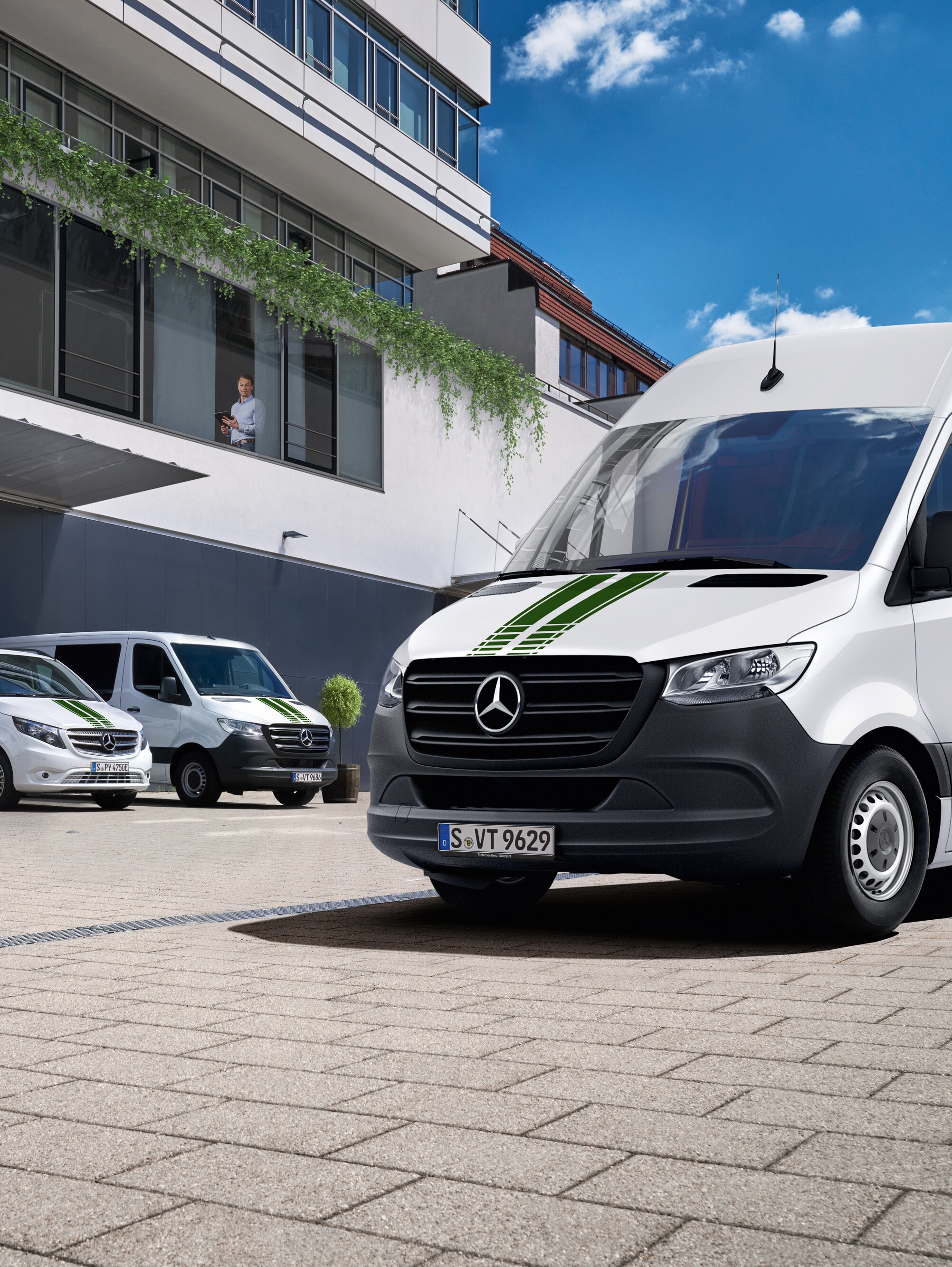 Une flotte d'utilitaires légers Mercedes-Benz devant un bâtiment, symbolisant le suivi numérique de la flotte.