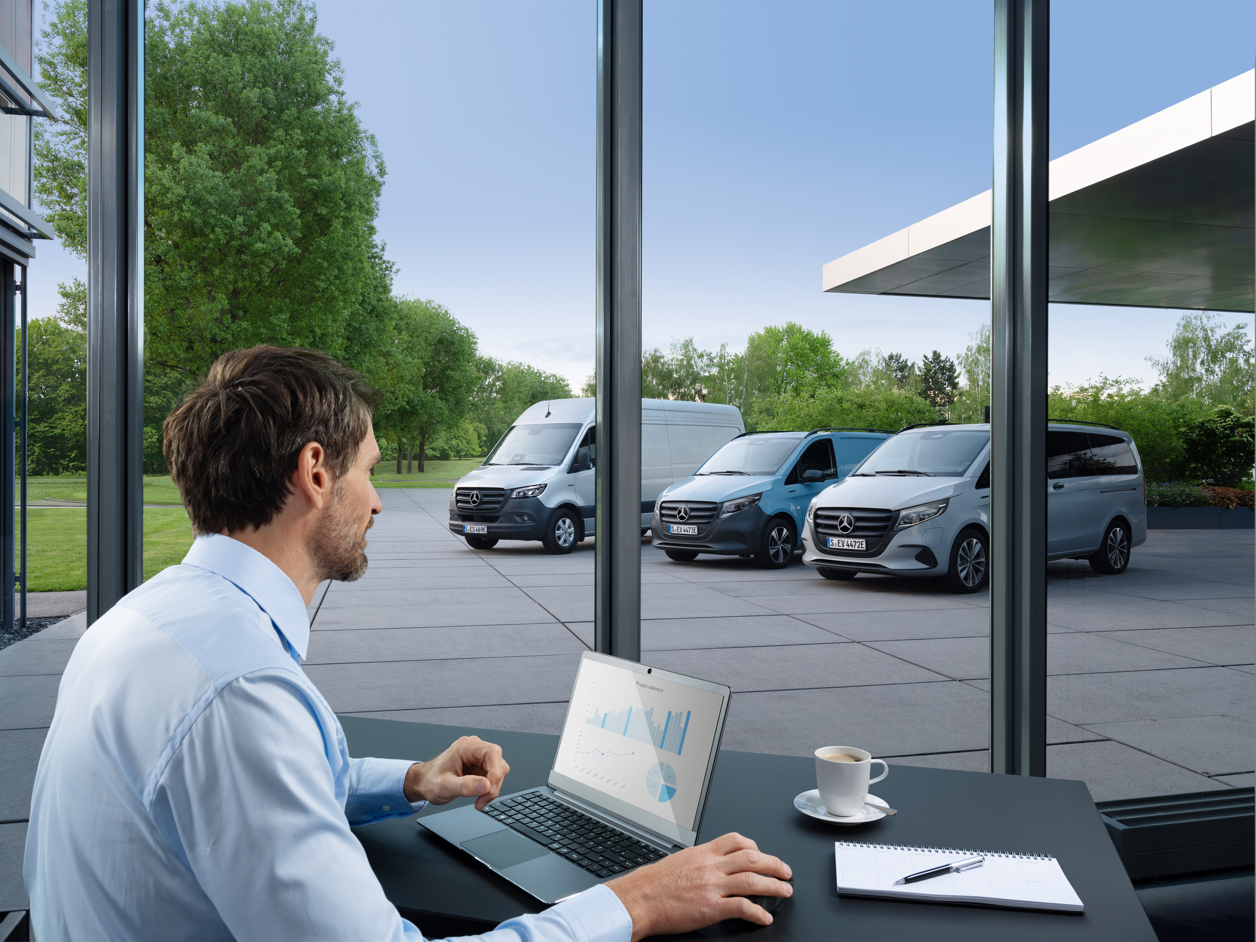 Mercedes-Benz | Transportertechnik | Van Uptime Monitor Ein Mann überwacht mehrere geparkte Mercedes-Benz Transporter mit einem Laptop, Symbol für digitales Fuhrparkmanagement.