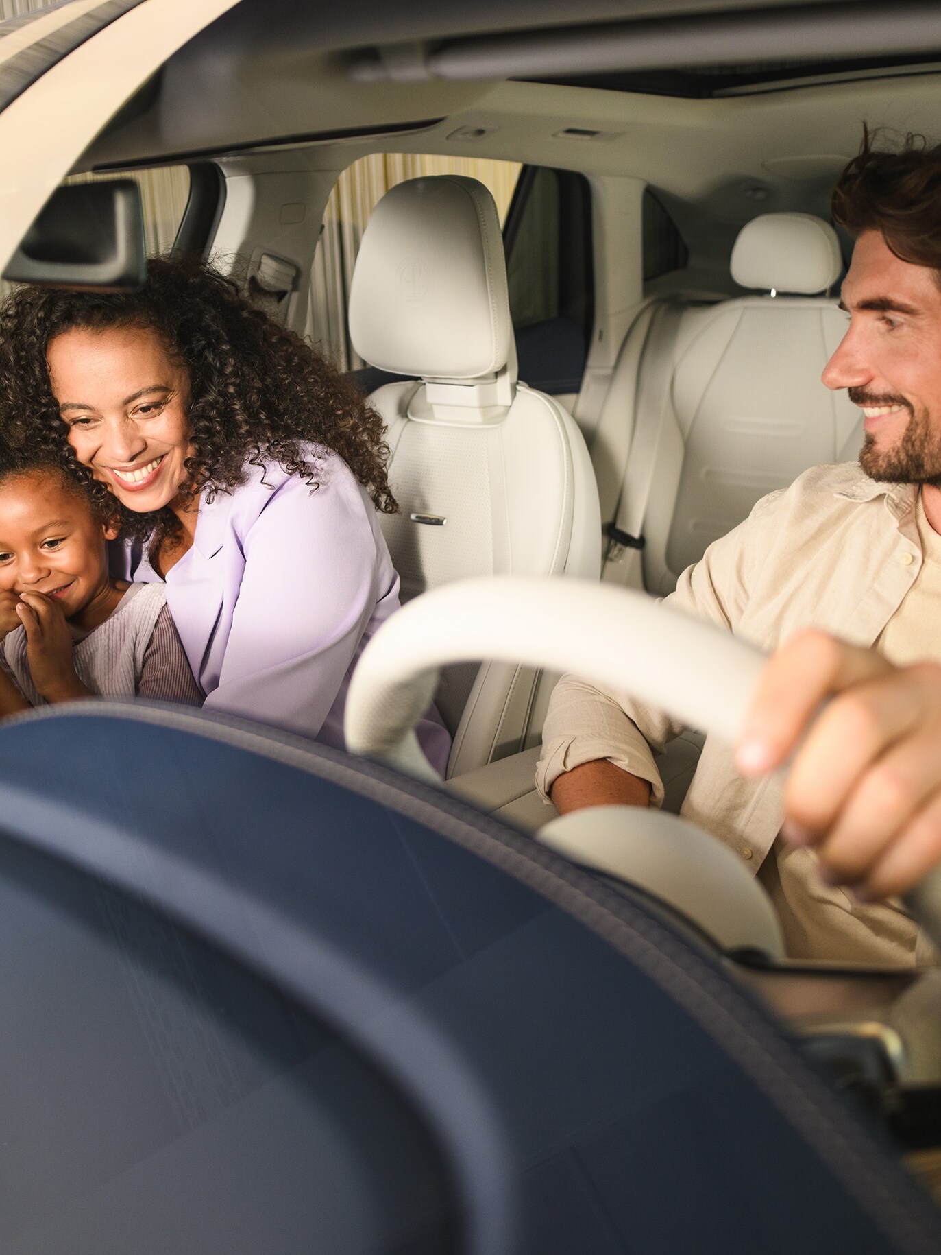 Zwei Personen und ein Kind in einem Mercedes-Benz-Fahrzeug.
