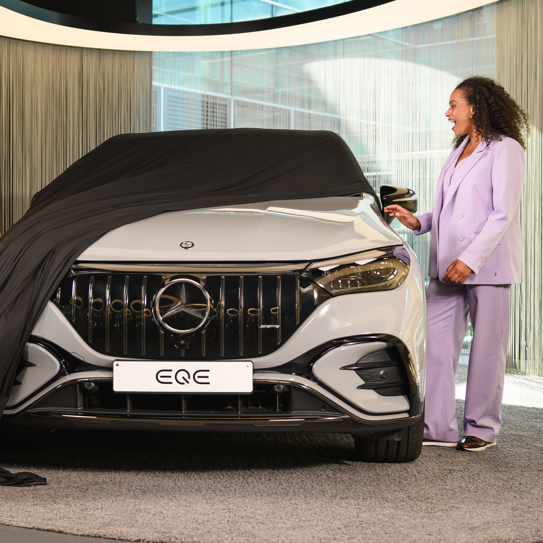 Offre de financement pour votre nouvelle Mercedes-Benz Deux personnes et un enfant retirant une housse d'un nouveau véhicule Mercedes-Benz dans un showroom.