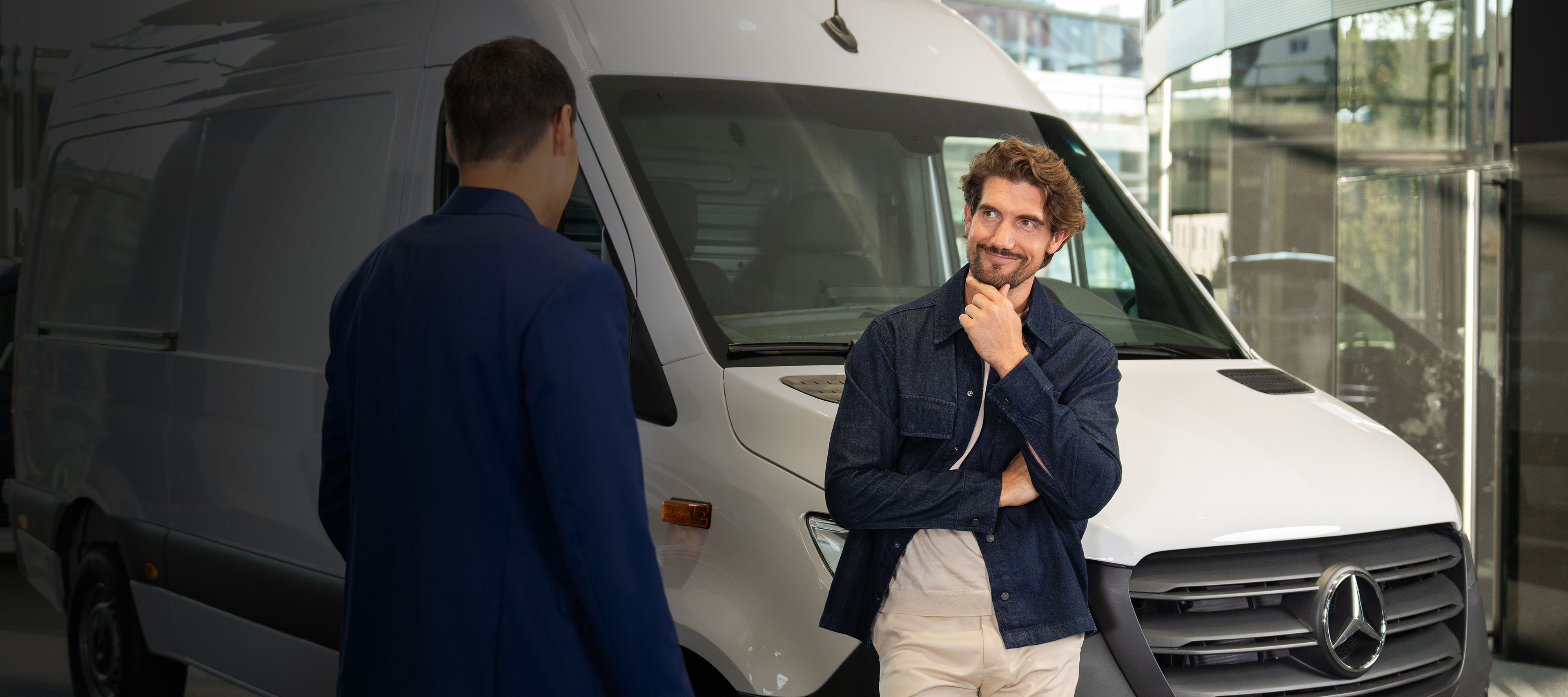 Client discutant d'un véhicule utilitaire avec un conseiller Client en discussion avec un conseiller à côté d'un véhicule utilitaire Mercedes-Benz blanc dans le showroom.