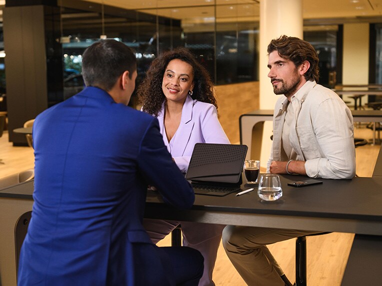 Trois personnes assises à une table en train de discuter.
