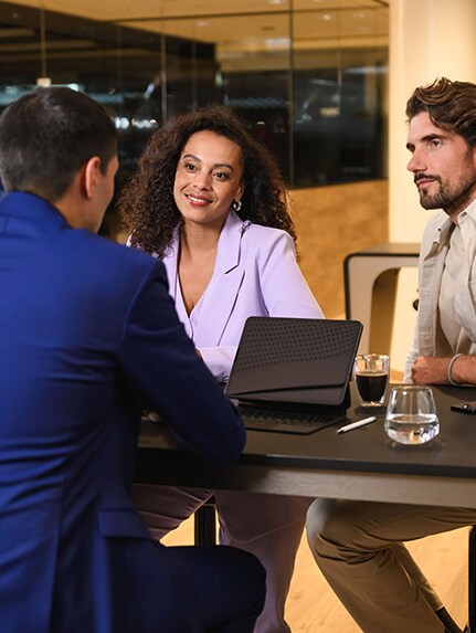 Drei Personen sitzen an einem Tisch und diskutieren