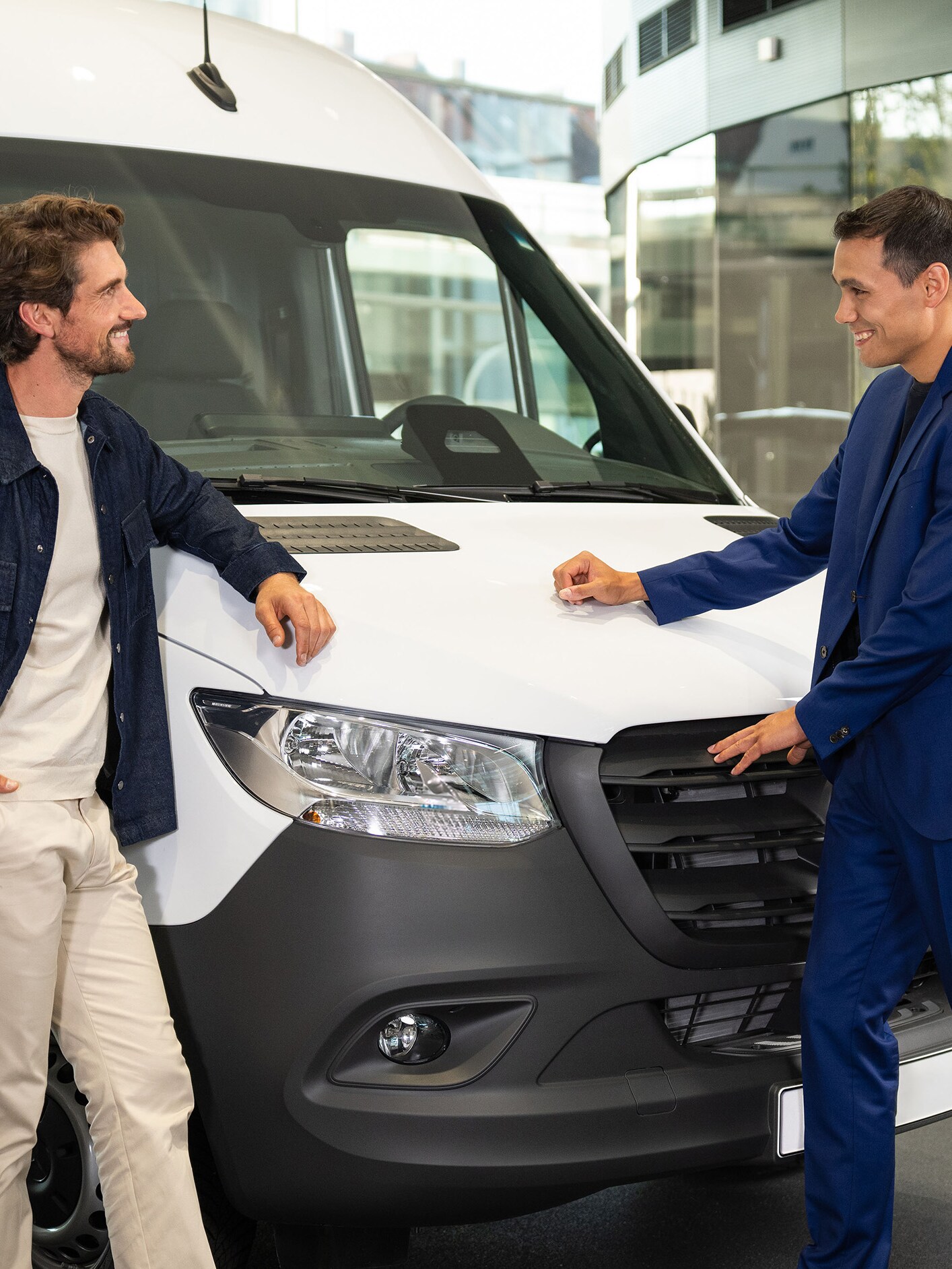 Deux personnes appuyées contre un utilitaire Mercedes-Benz et en train de converser.