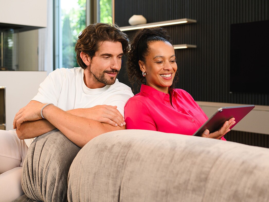 Un couple consulte ensemble les options de financement pour une Mercedes-Benz sur une tablette depuis son salon.