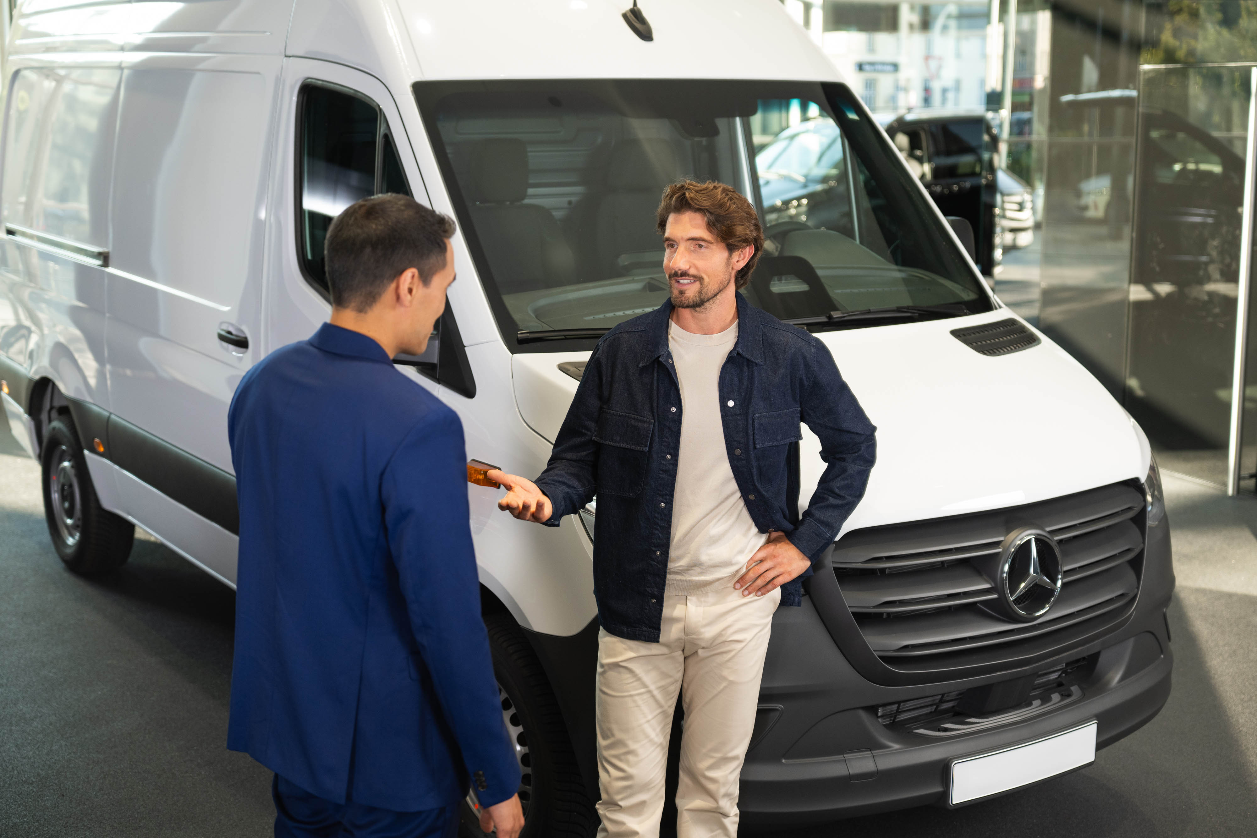 Des hommes discutent d’un fourgon Mercedes-Benz Deux hommes près d’un fourgon Mercedes-Benz blanc.