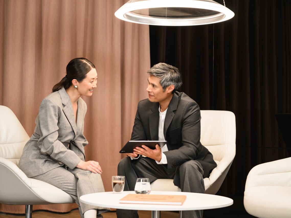 Deux clients professionnels discutent des possibilités en matière de véhicules utilitaires dans un espace lounge confortable.